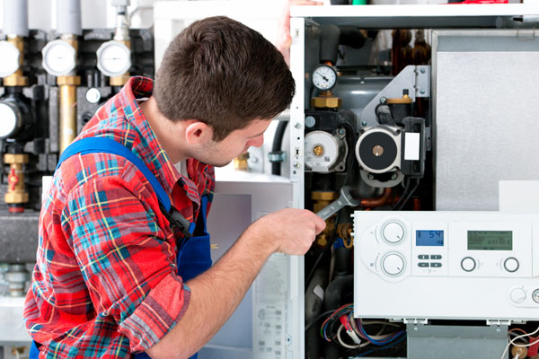HVAC technician inspecting and repairing boiler controls in Westminster