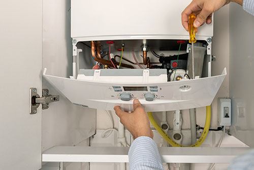 HVAC technician repairing an indoor boiler in Westminster