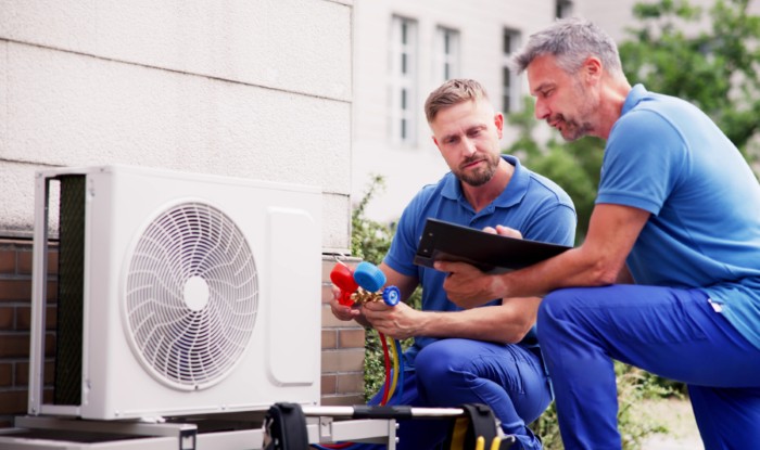 HVAC technicians installing an outdoor air conditioning unit in Westminster